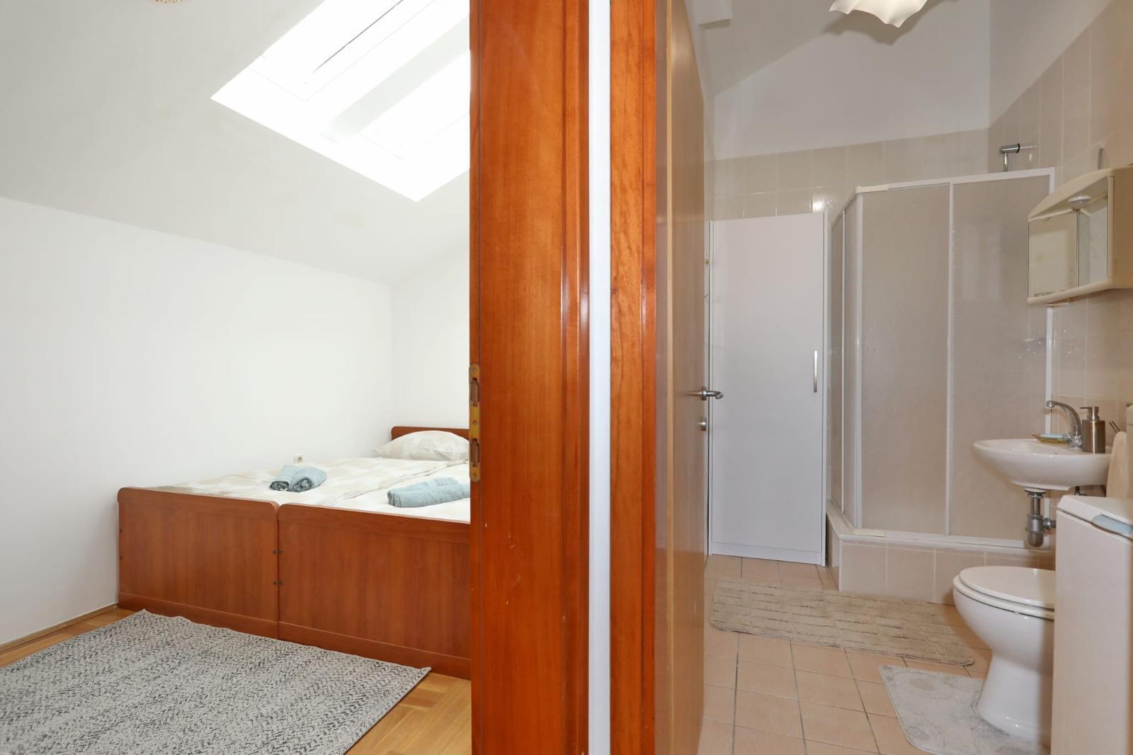 Apartman Gumbek — spavaonica pod krovnim prozorom i kupaonica s tuš kabinom
